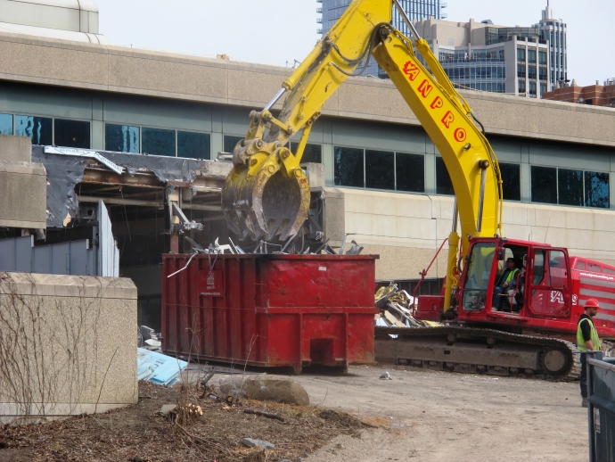 Shears on large excavator tearing materials down from law library exterior
